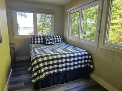 a small room with a bed and two windows at Olga's Bay Lakehouse in Minett