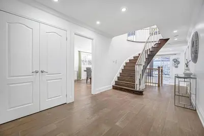 a white hallway with a staircase in a house at 166 Main - Family Getaway 5BR Home with Backyard & Parking in Markham