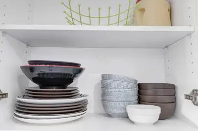 a shelf with a stack of plates and bowls at 166 Main - Family Getaway 5BR Home with Backyard & Parking in Markham