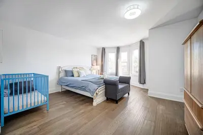 a bedroom with a crib and a bed and a chair at 166 Main - Family Getaway 5BR Home with Backyard & Parking in Markham