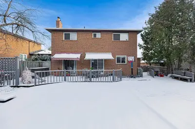 a brick house with a fence in the snow at 166 Basement - Cozy 3BR Markham Stay, Patio, Parking, Pet-Free in Markham