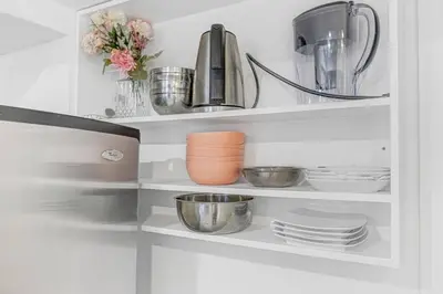 a white cabinet with plates and bowls and a blender at 166 Basement - Cozy 3BR Markham Stay, Patio, Parking, Pet-Free in Markham