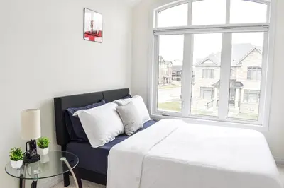 a bedroom with a bed and a large window at Spacious 4BR Home with EV Charger in Cambridge