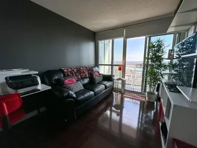 a living room with a leather couch and a large window at CityPlace Lofts Free Parking in Toronto