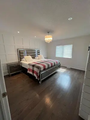 a bedroom with a bed and a chandelier at Warm Stylish 4 Bedroom Home 3 Bath in Ajax