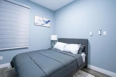 a bedroom with blue walls and a bed with pillows at Quiet, Soundproof 1-BR Suite Near Victoria Hospital with Parking & Balcony in London