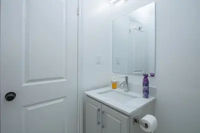 a white bathroom with a sink and a mirror at Quiet, Soundproof 1-BR Suite Near Victoria Hospital with Parking & Balcony in London