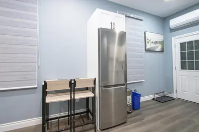 a stainless steel refrigerator in a room with a chair at Quiet, Soundproof 1-BR Suite Near Victoria Hospital with Parking & Balcony in London