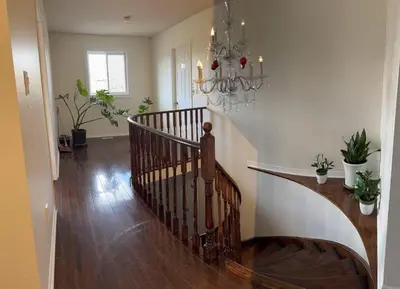a hallway with a staircase with a chandelier at Private Bright cozy bedroom in Mississauga