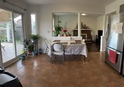a living room with a table and a refrigerator at Private Bright cozy bedroom in Mississauga