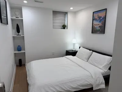 a white bedroom with a large bed with white walls at Studio 8848 - Sleeps 8 in Brampton