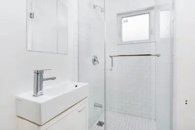 a white bathroom with a sink and a shower at Chic 3BR Ossington Hub Near Subway & Shops in Toronto