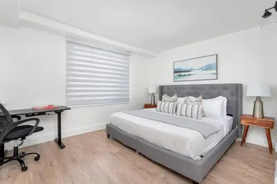 a white bedroom with a bed and a desk at Chic 3BR Ossington Hub Near Subway & Shops in Toronto