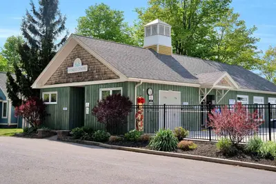 a green house with a black fence at The Juniper - 43 Butternut in Cherry Valley