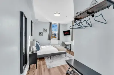 a white bedroom with a bed and a desk at Guestic at Queen West in Toronto