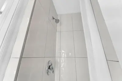 a shower in a bathroom with white tiles at Guestic at Queen West in Toronto