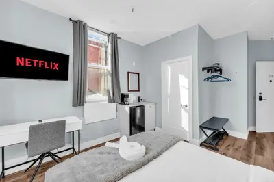 a bedroom with a white bed and a desk and a desk at Guestic at Queen West in Toronto