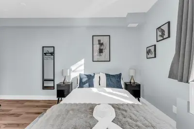 a white bedroom with a large bed with blue pillows at Guestic at Queen West in Toronto