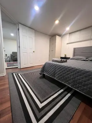a bedroom with a bed and a black and white rug at Charming 2 Bedroom Basement Apartment in Toronto