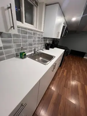 a kitchen with white cabinets and a sink at Charming 2 Bedroom Basement Apartment in Toronto