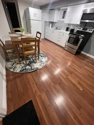 a kitchen and dining room with a table and a wooden floor at Charming 2 Bedroom Basement Apartment in Toronto