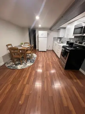 a kitchen and dining room with a table and a stove at Charming 2 Bedroom Basement Apartment in Toronto