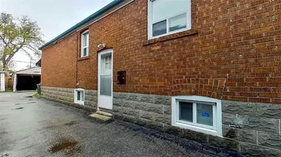 a brick building with a white door and windows at Charming 2 Bedroom Basement Apartment in Toronto