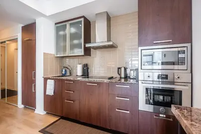 a large kitchen with wooden cabinets and appliances at Stunning Lake and CN Tower View with 2BR 2BA Free Parking in Toronto