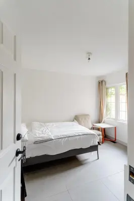 a white bedroom with a bed and a window at Zen-out Home in Mississauga
