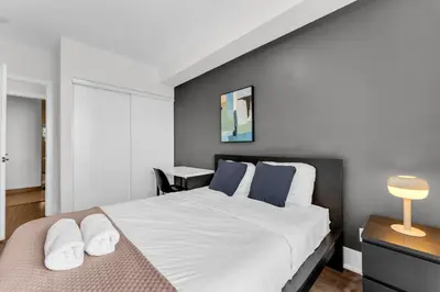 a bedroom with a large white bed with blue pillows at Eleve Toronto Residences in Toronto