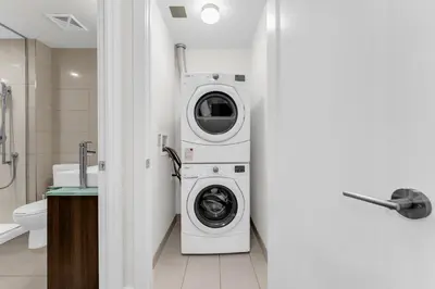 a washing machine in a bathroom next to a toilet at Eleve Toronto Residences in Toronto