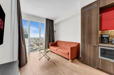 a living room with a couch and a large window at Eleve Toronto Residences in Toronto