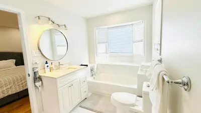 a white bathroom with a tub and a sink and a mirror at Bright 3BR Home in Richmond Hill free parking in Richmond Hill