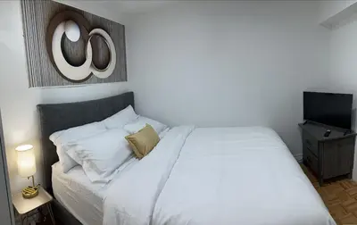 a bedroom with a white bed and a flat screen tv at Brand New Comfortable and Cozy Apartment near the Airport in Toronto
