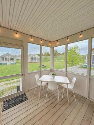 a dining room with a table and chairs and windows at The Magnolia - 37 Butternut in Cherry Valley