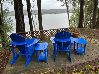 a group of blue chairs and a table next to a lake at Rustic and Spacious Lakefront Oasis in Nature in Algonquin Highlands
