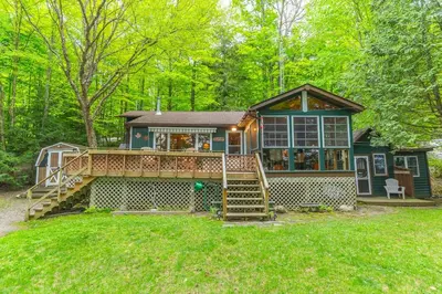 a home with a large deck and a house at Rustic and Spacious Lakefront Oasis in Nature in Algonquin Highlands