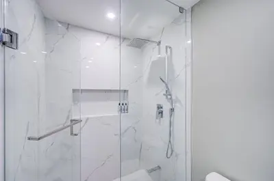 a white bathroom with a shower with a glass door at Cozy Studio with 2 Beds & Private Bathroom in Toronto