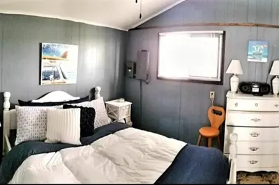 a bedroom with a bed and a dresser and a window at Sandbanks Beach Cottage in West Lake