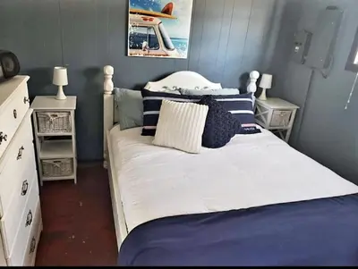 a bedroom with a large white bed with blue walls at Sandbanks Beach Cottage in West Lake