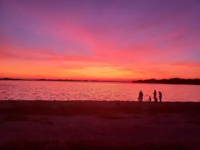 a group of people standing on the shore of a lake at Sandbanks Beach Cottage in West Lake