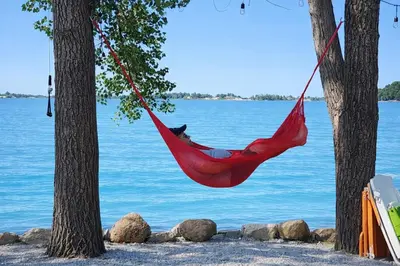 a man in a red hammock hanging between two trees at Sandbanks Beach Cottage in West Lake