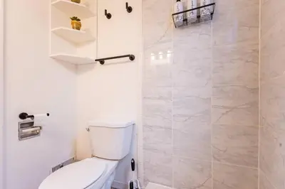 a white bathroom with a toilet and a shower at 2min to DT, Cowboys, Full-Kitchen, 65 inch TV in London