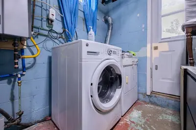 a washing machine in a room with a blue wall at 2min to DT, Cowboys, Full-Kitchen, 65 inch TV in London
