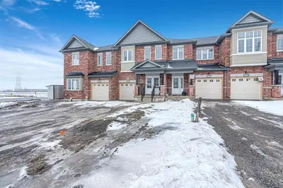 a brick house with two garage doors in the snow at Spacious 3BR House with Modern Comforts in Thorold