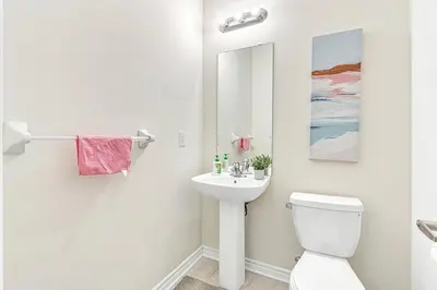 a bathroom with a white toilet and a sink at Spacious 3BR House with Modern Comforts in Thorold