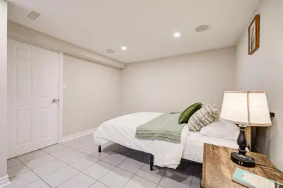 a bedroom with a bed and a table and a lamp at Lower-Level Classic House in Richmond Hill in Richmond Hill