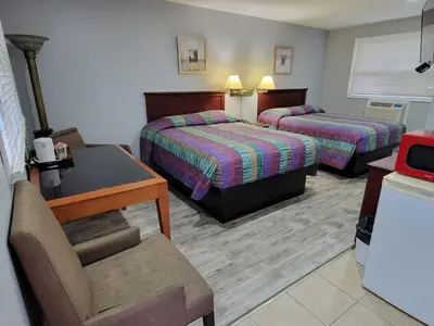 a hotel room with two beds and a chair at Cobourg Inn in Cobourg