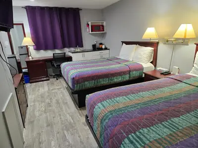 a hotel room with two beds and a desk at Cobourg Inn in Cobourg