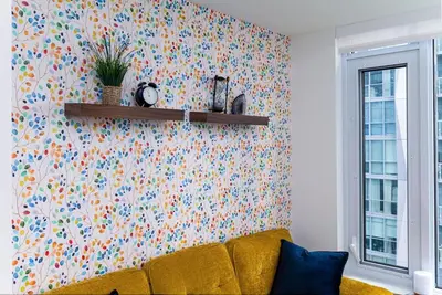 a living room with a yellow couch and a floral wallpaper at Stylish Yorkville Condo Sleeps 3 Prime Location in Toronto